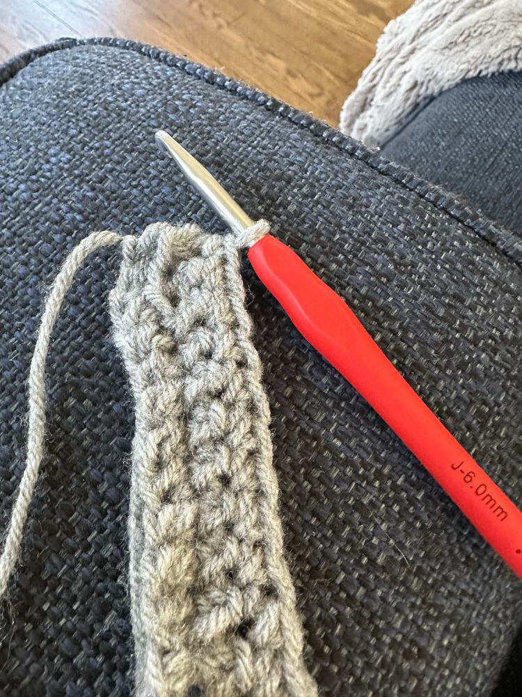 Red crochet needle with several rows of grey crochet 