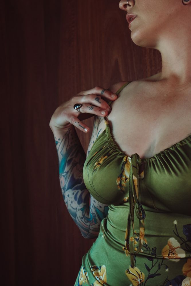 An image of Frankie's torso & lower face in a form fitting green slip dress