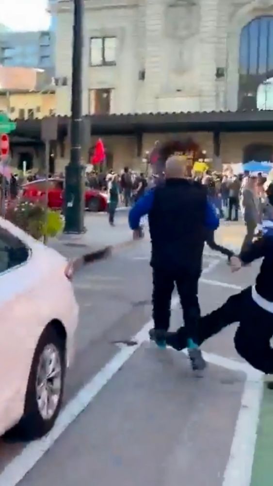 Still from the video. Old white dude charging, while a protester's right leg is entering the frame from the right