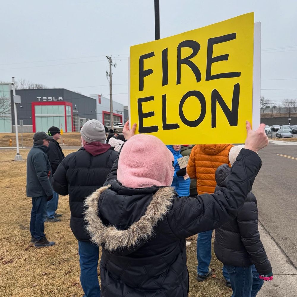 A person holds a sign that says “Fire Elon” at a protest against Elon Musk outside of a test dealership in Golden Valley, Minnesota. 