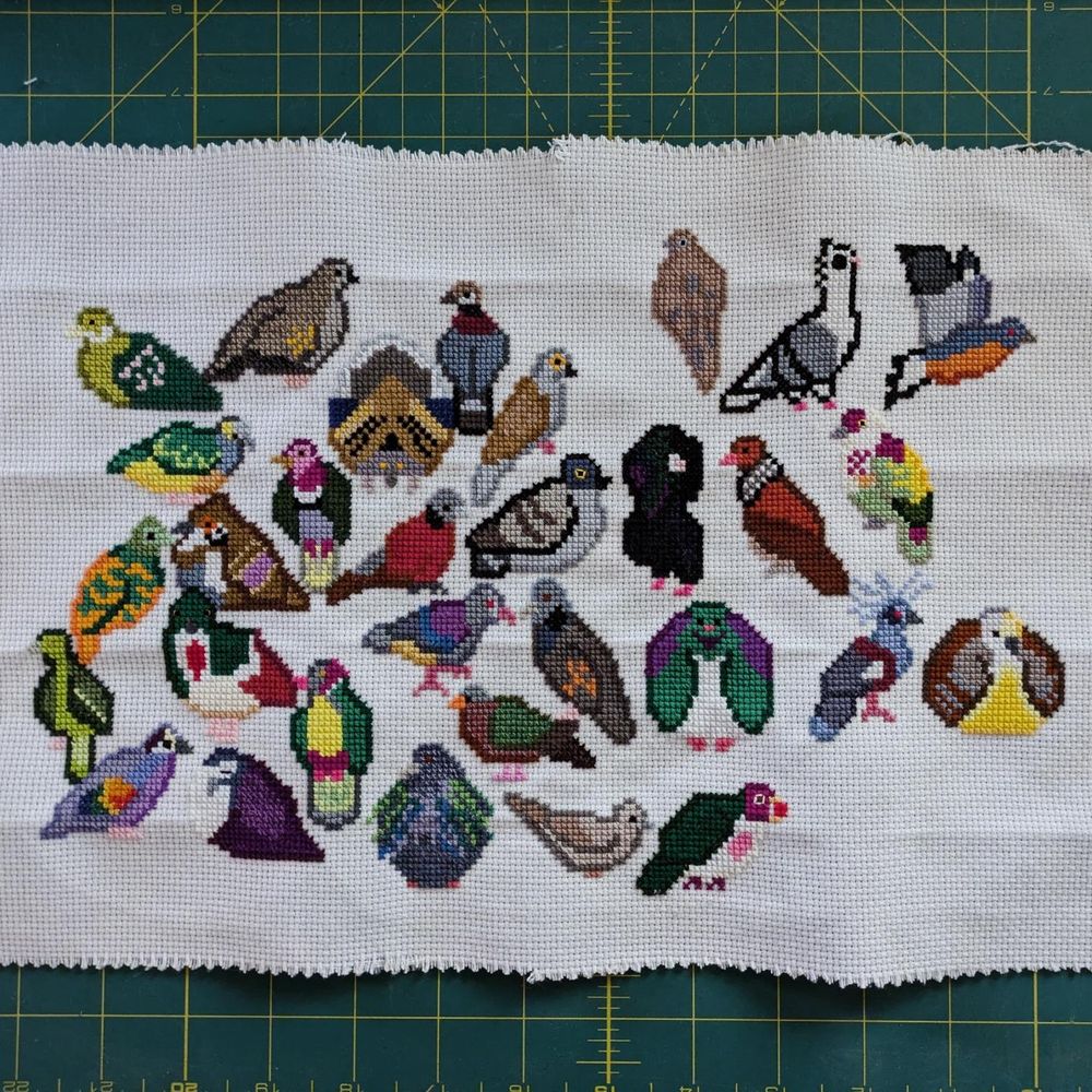 The finished piece featuring allll of the pigeons and doves in cross stitch!
