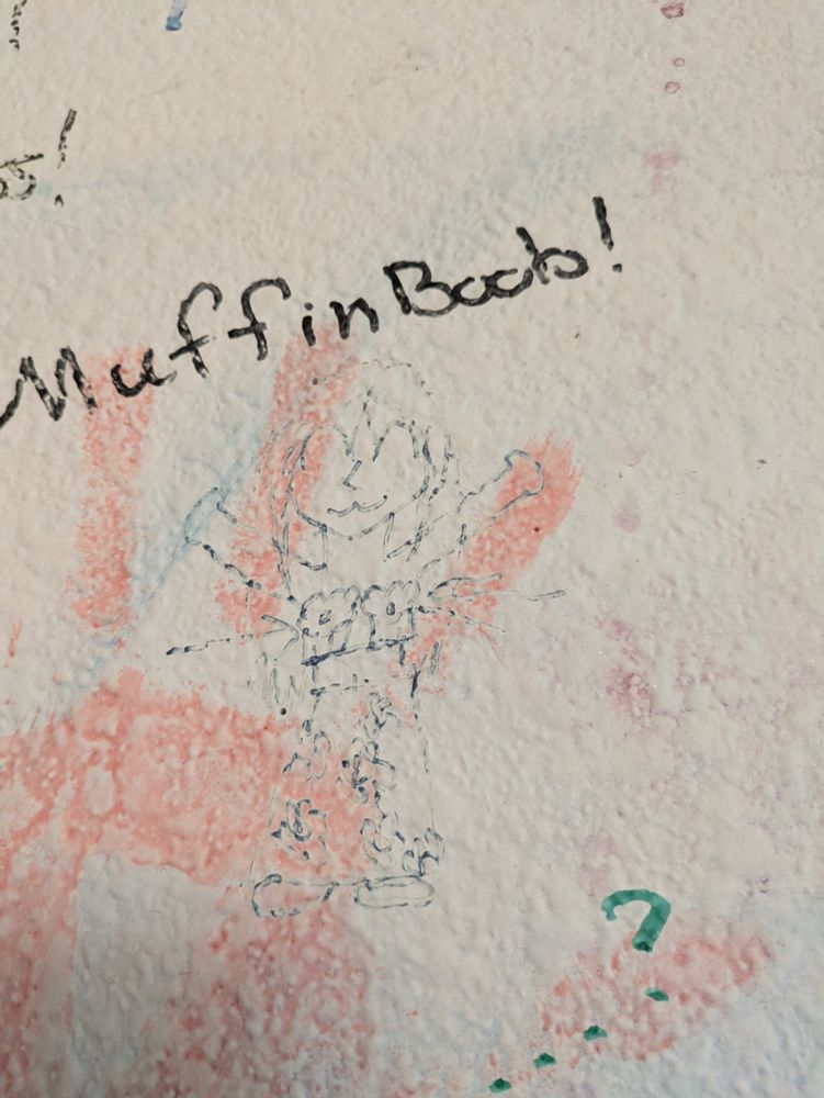 A very faded cartoon girl stands with her arms above her head. Instead of boobs she has muffins where her boobs should be. The words 'Muffin Boob' is written above her in black sharpie.