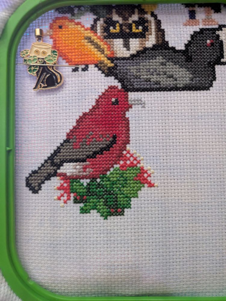 A cross stitched piece featuring an ʻApapane and Ohi’a Lehua flowers.