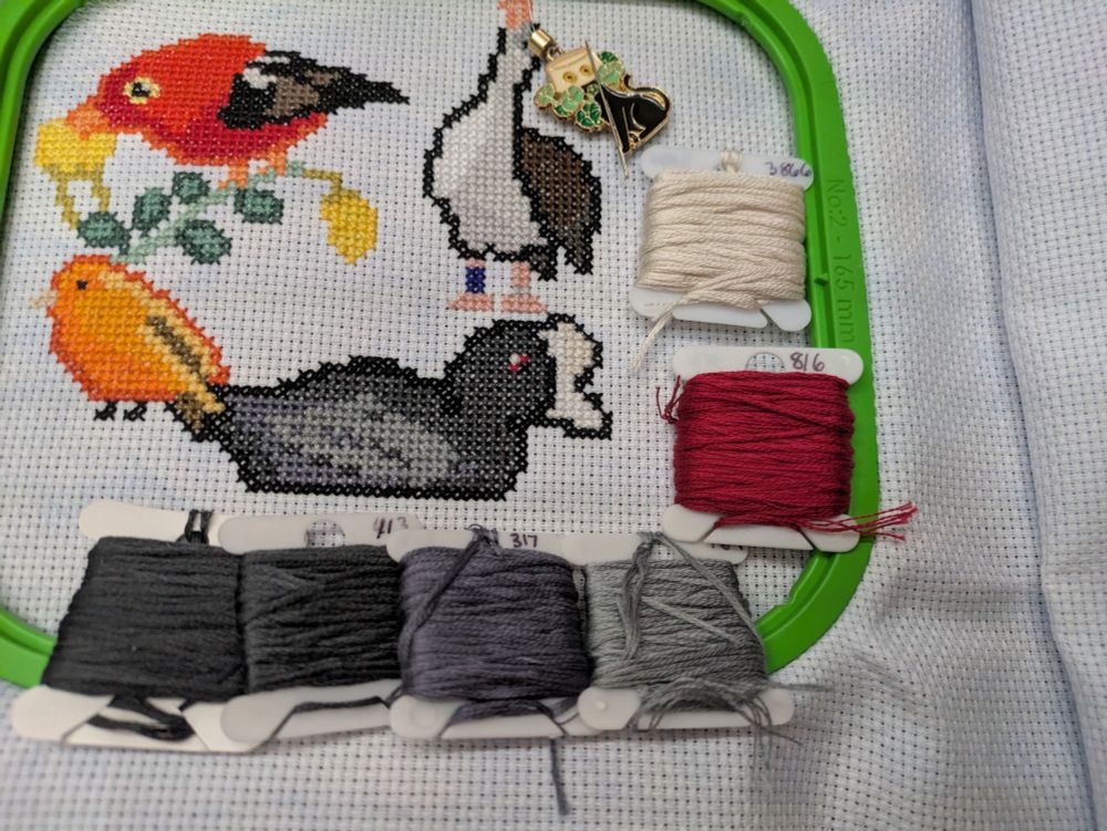A cross stitch of a Hawaiian coot with accompany bobbins
