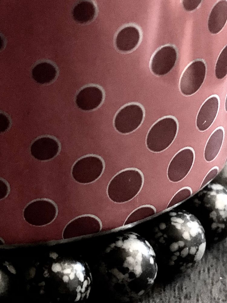 A picture of a Can that has red dots in lines, sitting on top of black and grey beads. 
