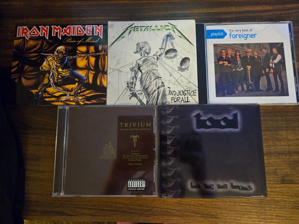 CDs from iron maiden, Metallica, foreigner, trivium, and tool