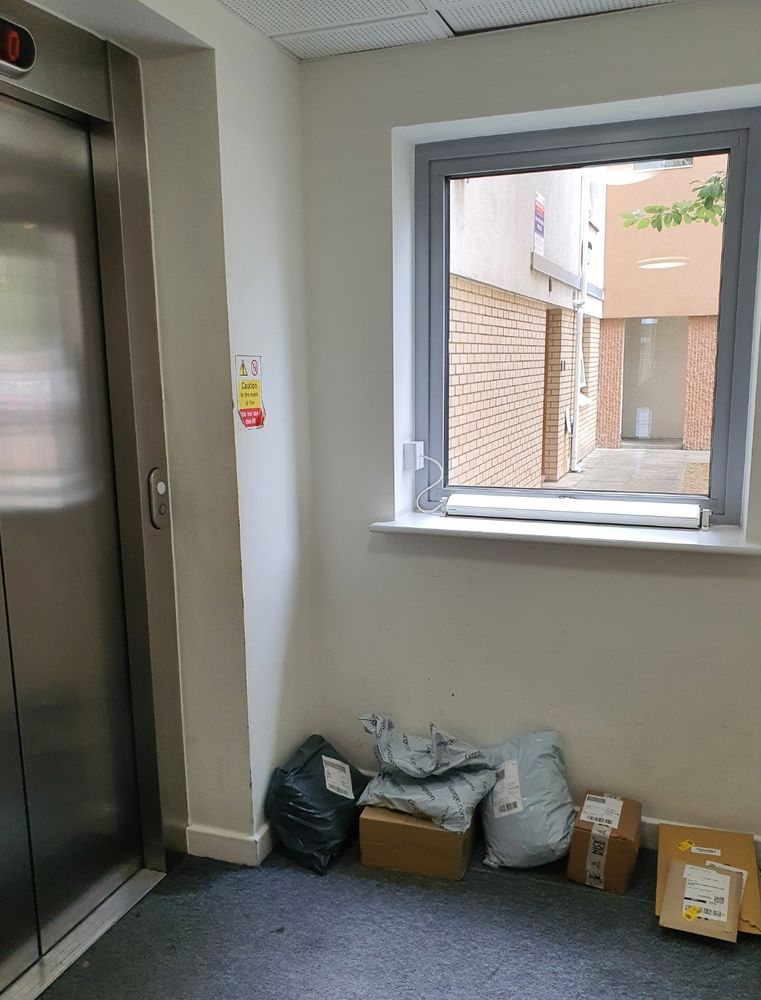 A photo of the floor by the lift. There are packages, some in little piles when there's more than one package for a specific flat.