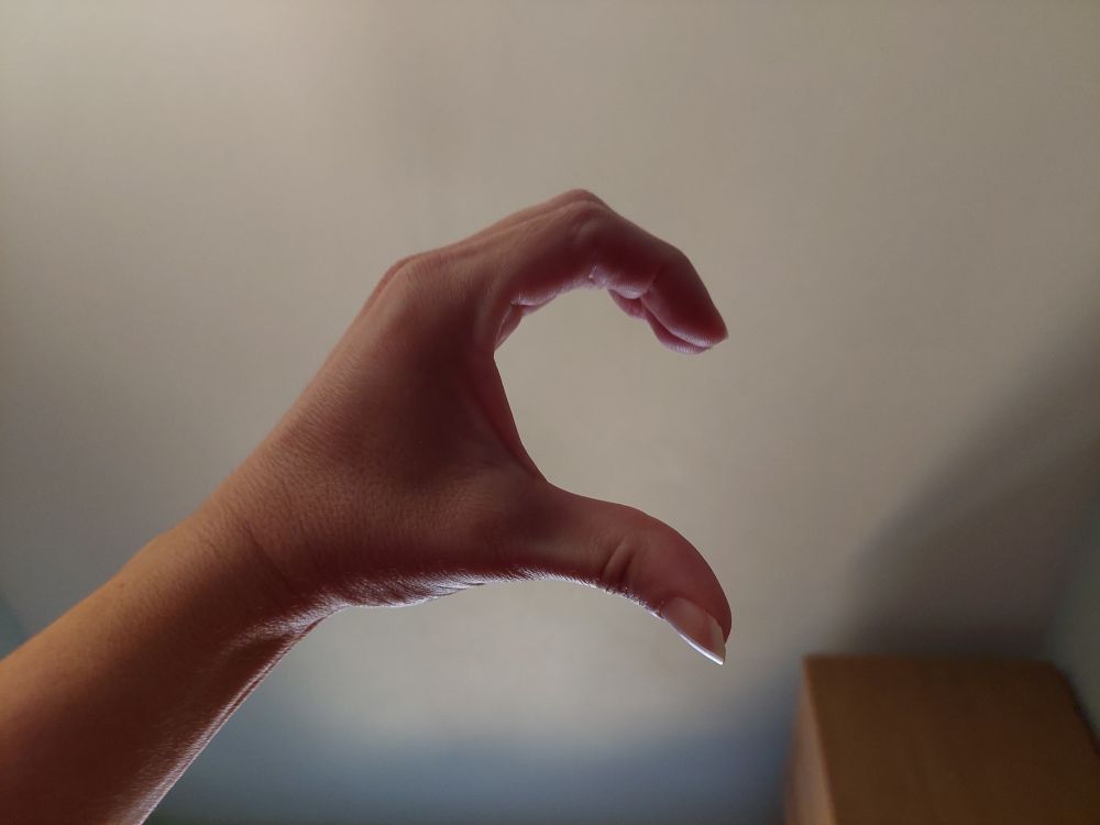 Mein linker Hand zu einem halben Herz geformt. Im Hintergrund die Zimmerdecke.