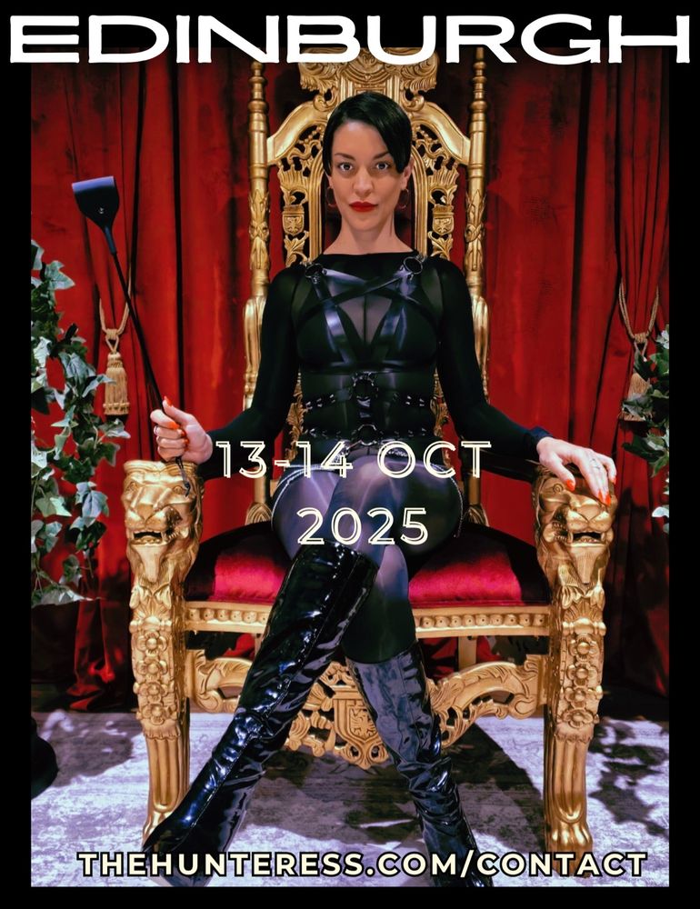The Hunteress is wearing a shiny body stocking, latex harness and pvc knee boots as she sits in a throne, with her legs crossed.  In her right hand she is holding a riding crop.  She will be in Edinburgh for sessions on the 13th and 14th of October. Applications to be made at her website www.thehunteress.com/contact