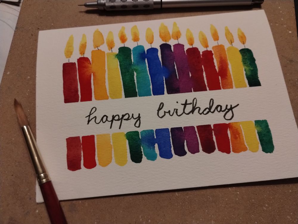 A hand painted birthday card with a series of rainbow candles.
