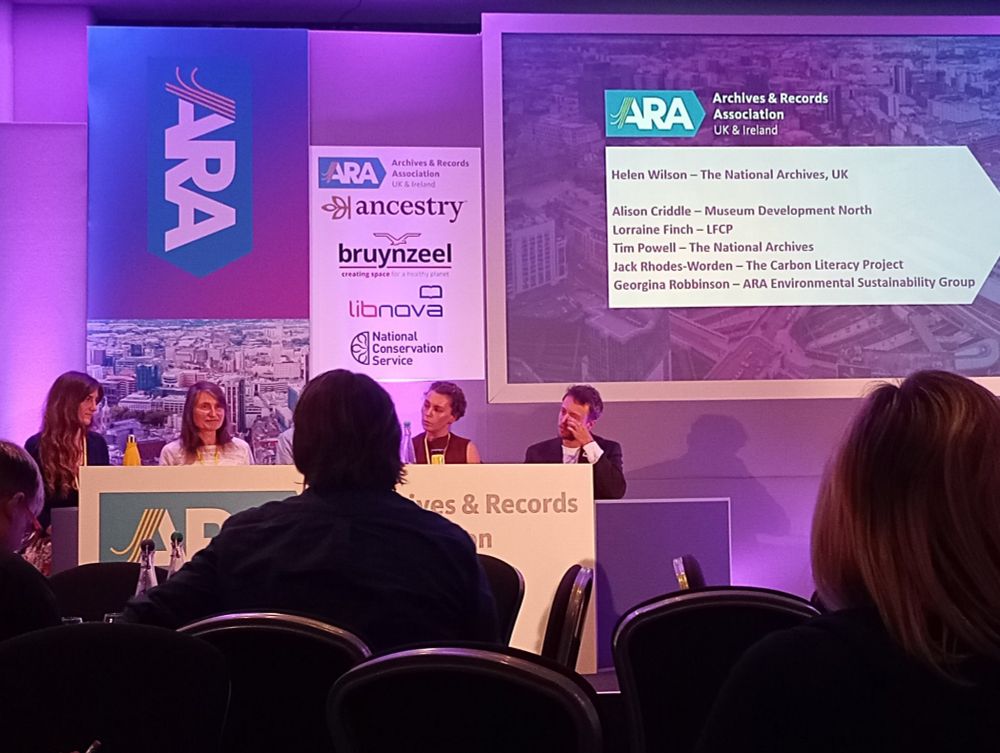 Colour photograph of four people participating in panel at ARA Conference 2024 as an audience looks on 