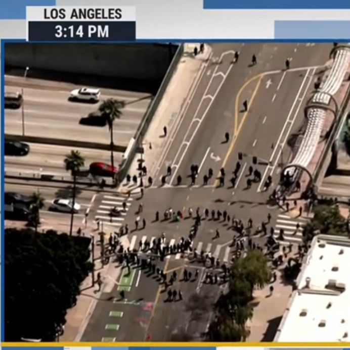 Protesters creating a four-lane peace sign with their bodies on an LA roadway. Defund ICE. 