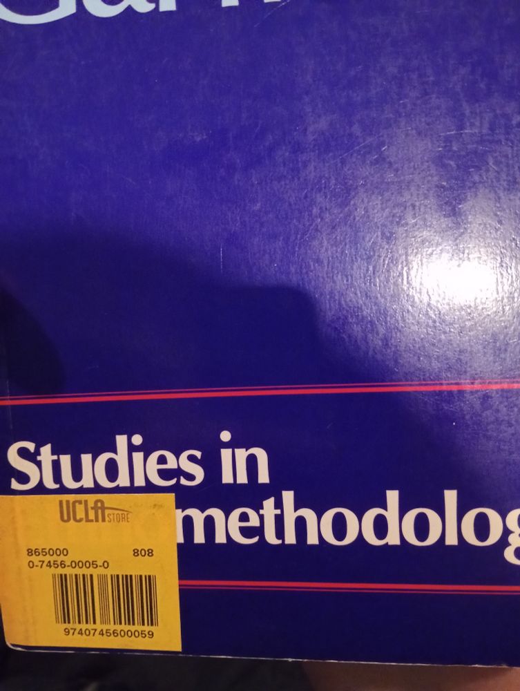 Close up the book cover. It is all purple except for a couple thin red lines between which is the white text saying "studies in ethnomethodology". In the bottom right of the cover is a yellow sticker with a barcode and the letters UCLA alongside other strings of numbers.