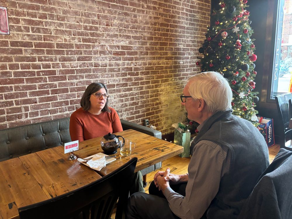 Gov. Evers sits at a table talking with local coffee shop owner. 