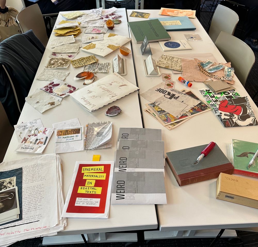 Table with material ephemera, syllabus, books with scalpels on top for book anatomy experiments, examples of experiments in organic books, and examples of weird books to explore at our panel