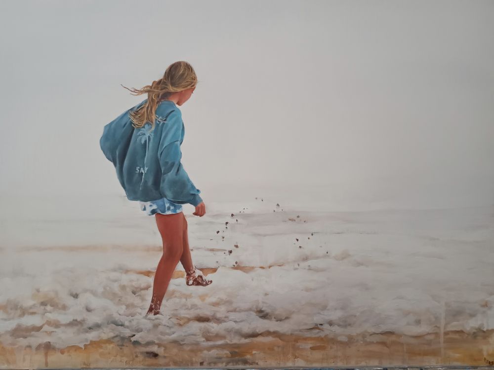 Painting of a girl wearing a blue sweatshirt kicking the sand in the edge of the sea