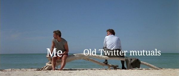The opening beach scene from Manhunter. Will Graham (played by William Petersen), in a t-shirt and shorts, and Jack Crawford (played by Dennis Farina) sit slightly apart on a branch of driftwood bleached white by the sun. Jack sits facing the sea, but with his head turned towards Will. Will sits with his back to the ocean, looking away from Jack. A caption over Will reads 'Me', while one over Jack reads 'Old Twitter mutuals'.