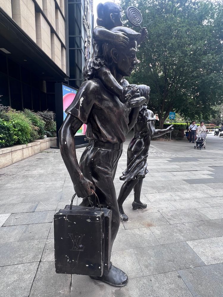 Wuhan statue of a man with his daughter on his shoulders and carrying a Louis Vuitton bag
