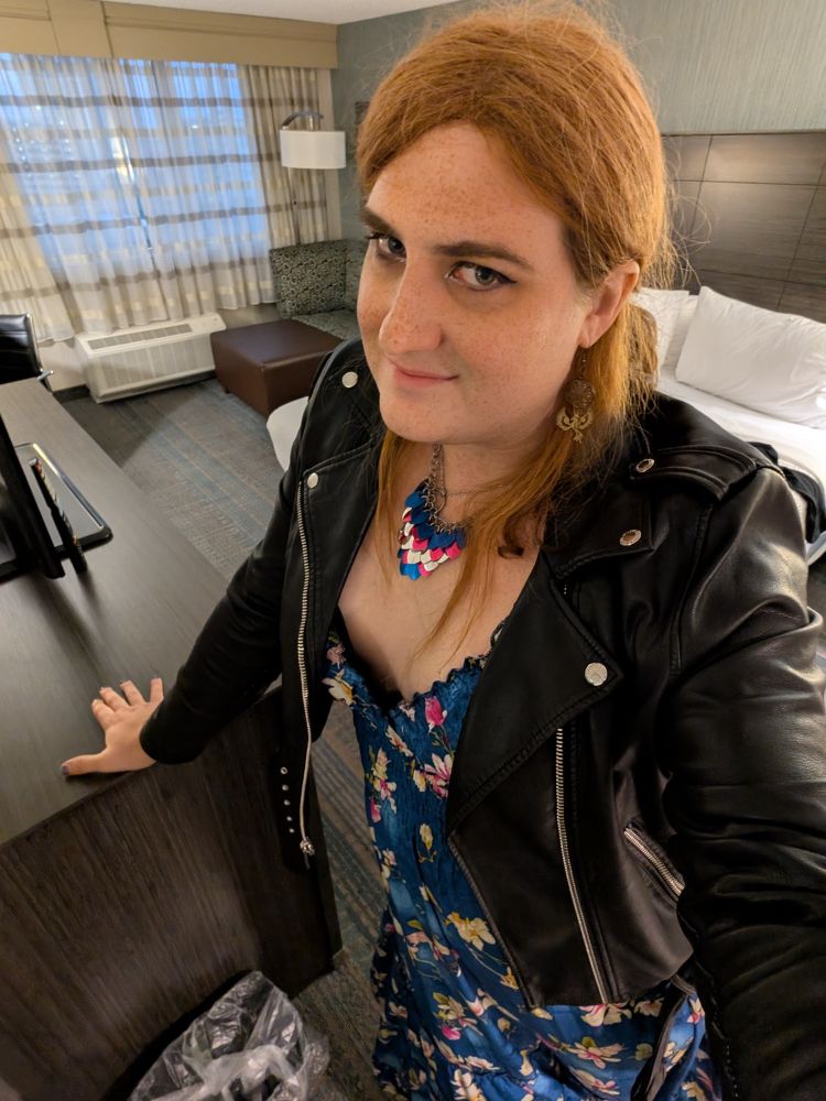 Alannah wearing a blue floral dress and a leather jacket 