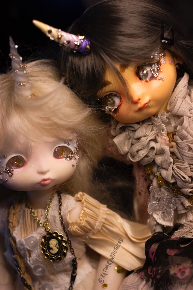 Two Do Dolls Dream teacup dolls. The sculpts are Aurie and Marie. They have unicorn horns and are dressed in maximalist fashion.