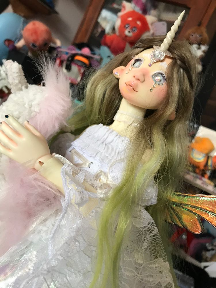 A sleepy sheepy doll head on a custom house 1/4 body. She has brown green hair with a white unicorn horn.