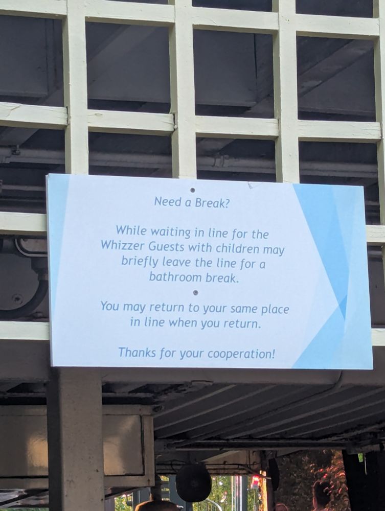 A sign that reads: "Need a Break? While waiting in line for the Whizzer, Guests with children may briefly leave the line for a bathroom break. You may return to your same place in line when you return. Thanks for your cooperation!"