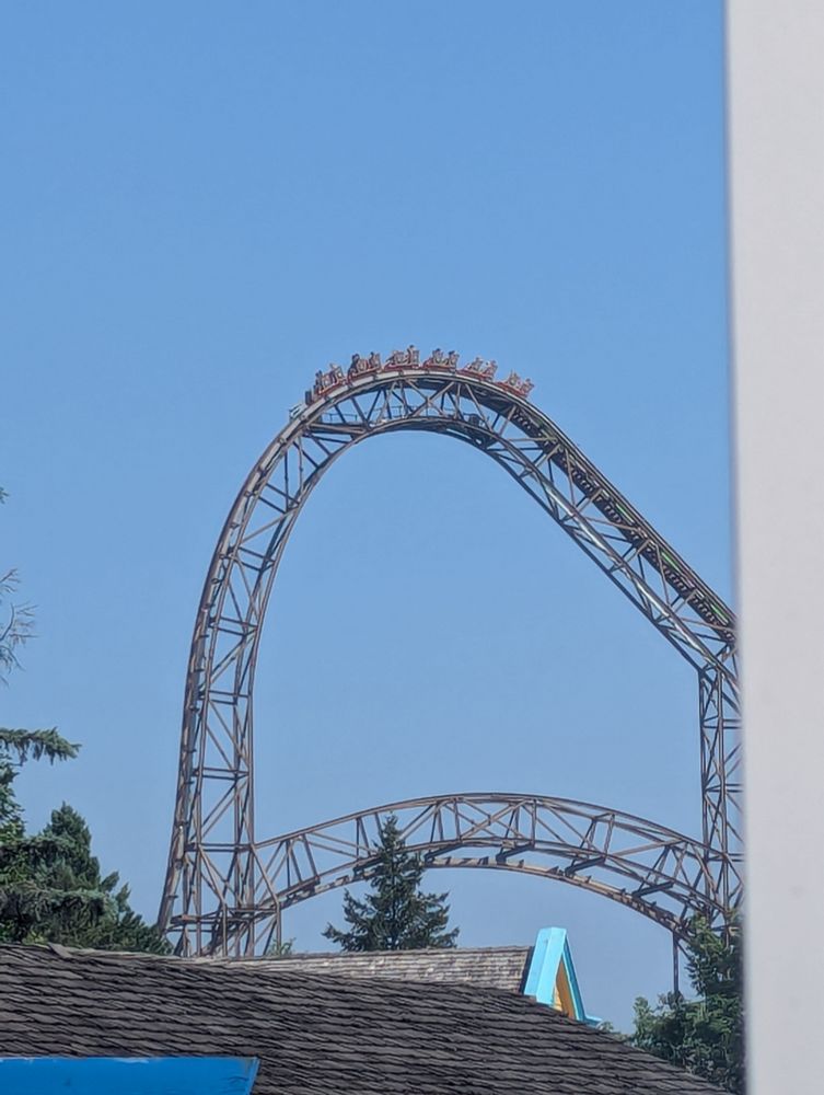 A picture of Goliath, a RMC wooden coaster (topper track) at Six Flags Great America. The train is cresting the top of the lift, which has a very unusual hollow structure underneath (this portion is steel structure)