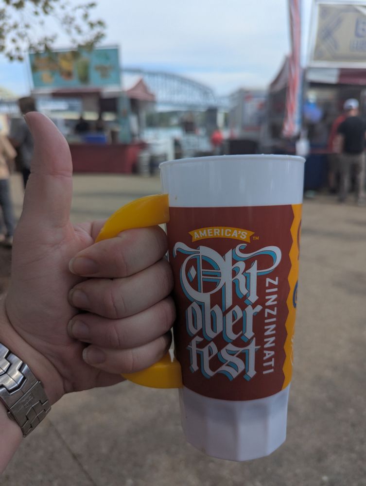 A photo of an Oktoberfest Zinzinnati mug held in a thumbs up by the cameraman