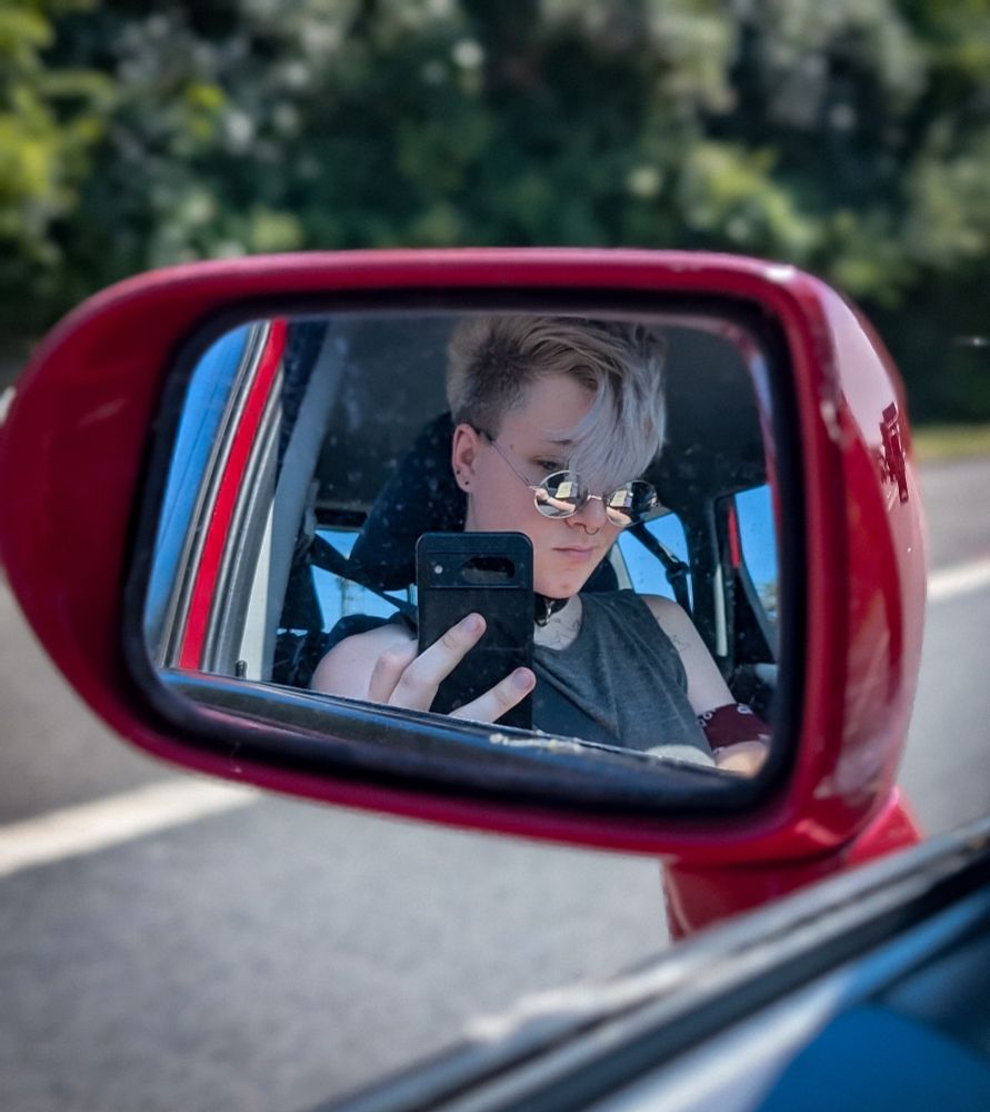 loki~ in the side mirror of a red car 