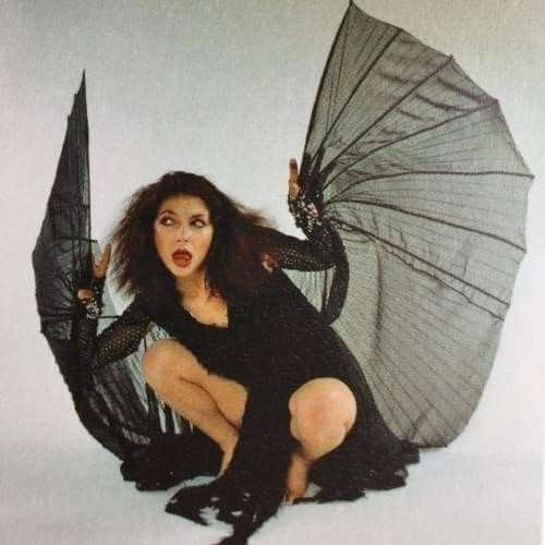 Kate Bush  com um vestido preto de mangas longas e tecido transparente colado aos braços imitando as asas de um morcego
