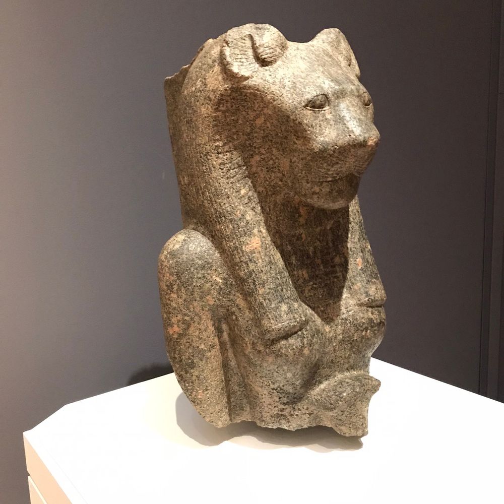 A brown stone sculpture of a lioness goddess in the NC Museum of Art. The Goddess Sekhmet is both a warrior and a healer.  