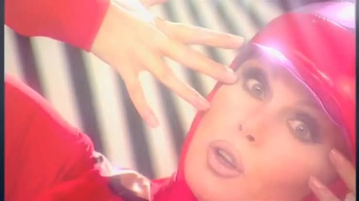 Patsy Stone in a red 60s mod outfit (in this scene she is being photographed and being told to say the word "Thursday") 