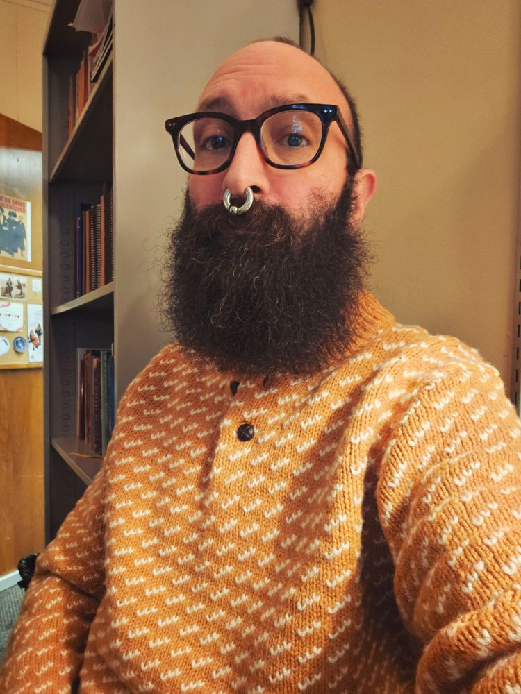 Me sitting in my office in a yellow bird's-eye style polo sweater with wooden buttons