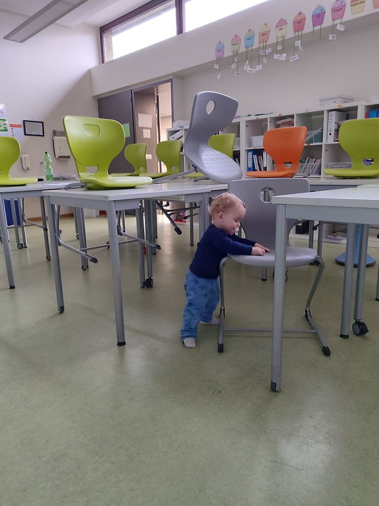 Einjährigee Sohn steht im leeren Klassenzimmer.