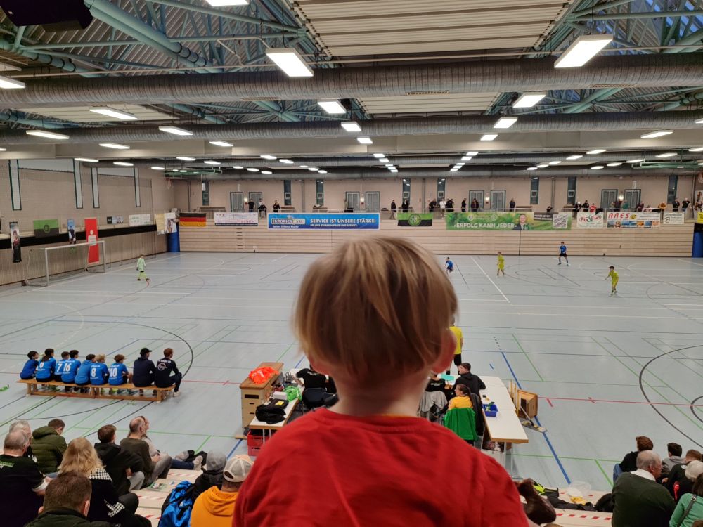 Hinterkopf meines zweijährigen Sohnes, wie er dem Hallenturnier zuschaut