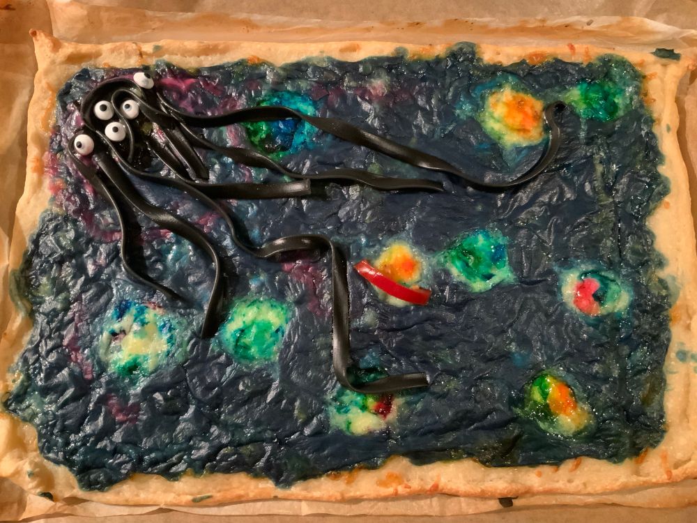 A galaxy pizza with crema nero, colourful planets and Cthulu like monster in the upper left corner. 