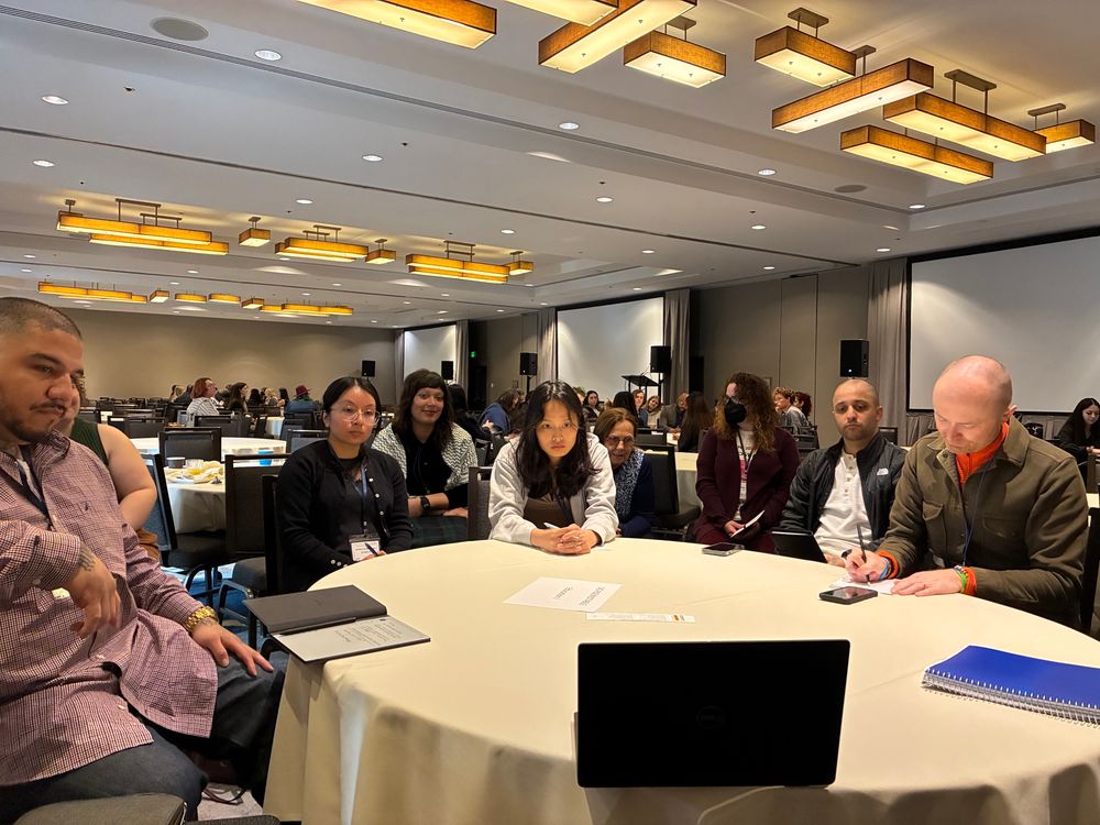 Roundtable attendees watch a presentation on a laptop.