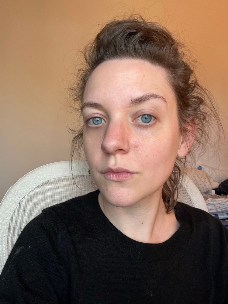 Em takes a selfie, staring at the camera, in a black sweater. 