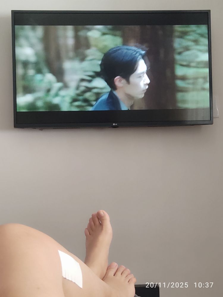 Assistindo Alquimia das Almas, a tv está na parede e é possível ver meus pés logo embaixo, em primeiro plano