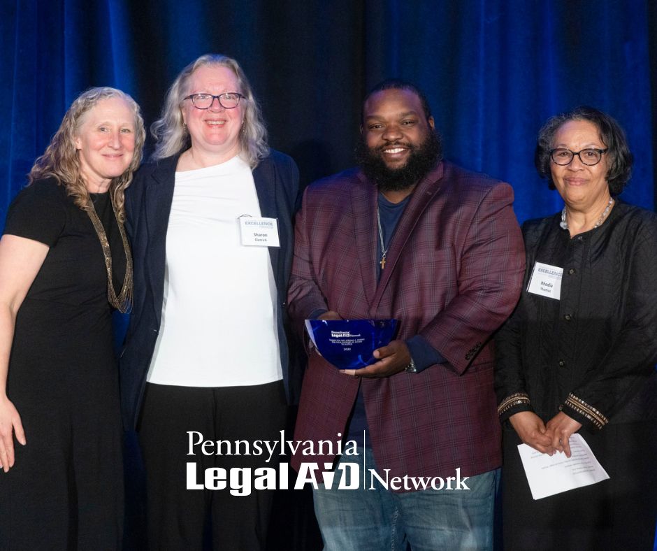 This is an image of PLAN, Inc. Executive Director Meredith Rapkin, Community Legal Services Litigation Director Sharon Dietrich, House Majority Appropriations Chairman Jordan Harris, and MidPenn Legal Services Executive Director Rhodia Thomas standing together at the 2025 Excellence Awards against a blue backdrop. Chairman Harris, who delivered the keynote address, holds a blue bowl that was given to him as a token of appreciation. The PLAN, Inc. logo appears at the bottom of the image.