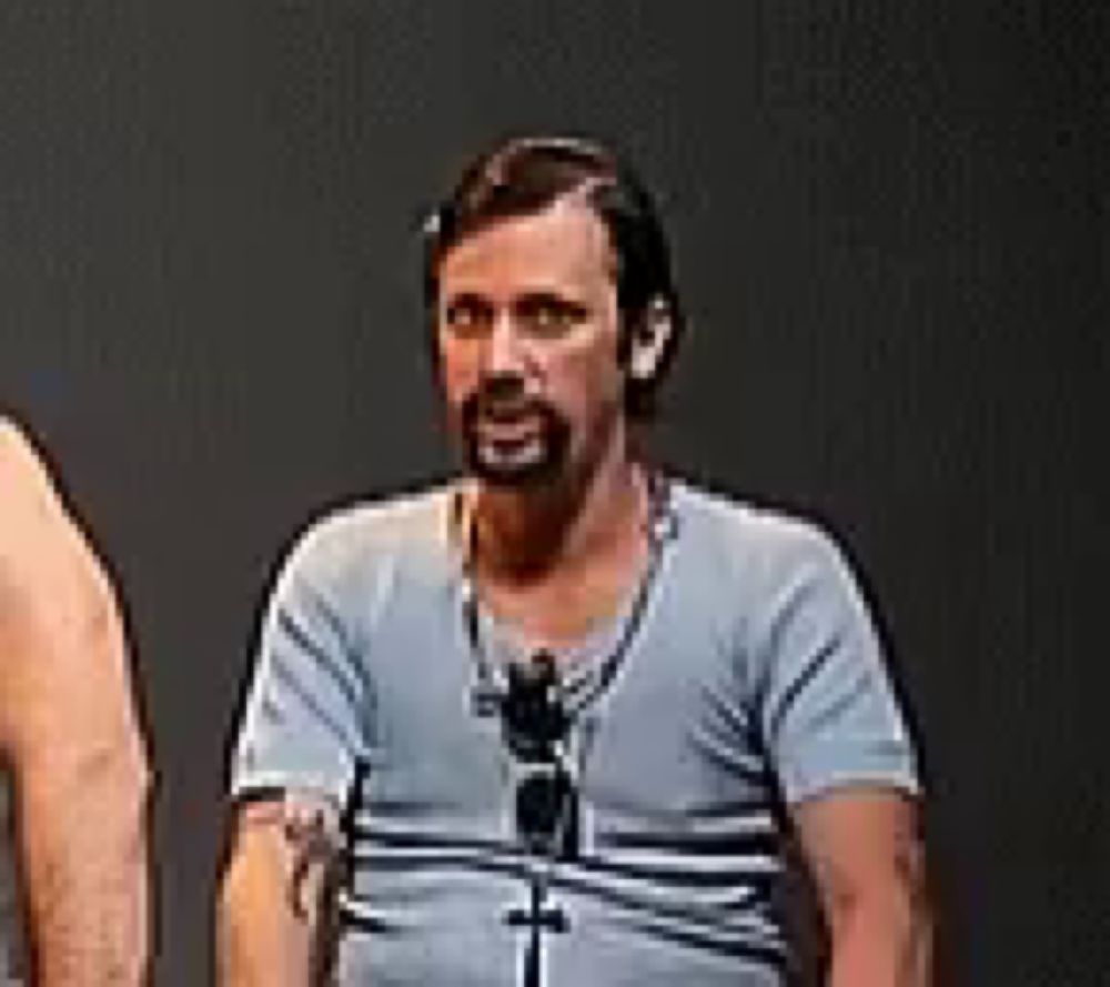 a man with a beard wearing a blue shirt and sunglasses is standing next to two other men .