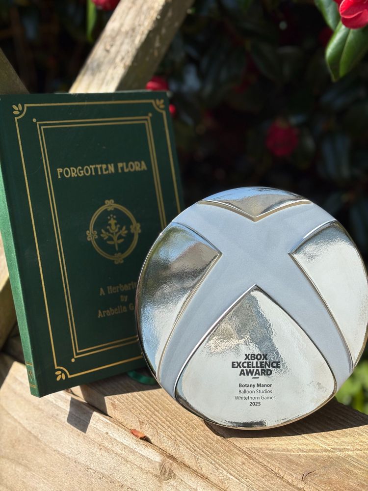 The herbarium book on the left side, and the xbox excellence award on the right side. In the background is a rose bush.