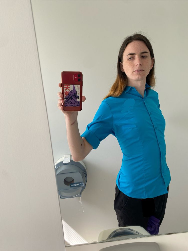 girl taking a mirror selfie in a blue buttoned up shirt