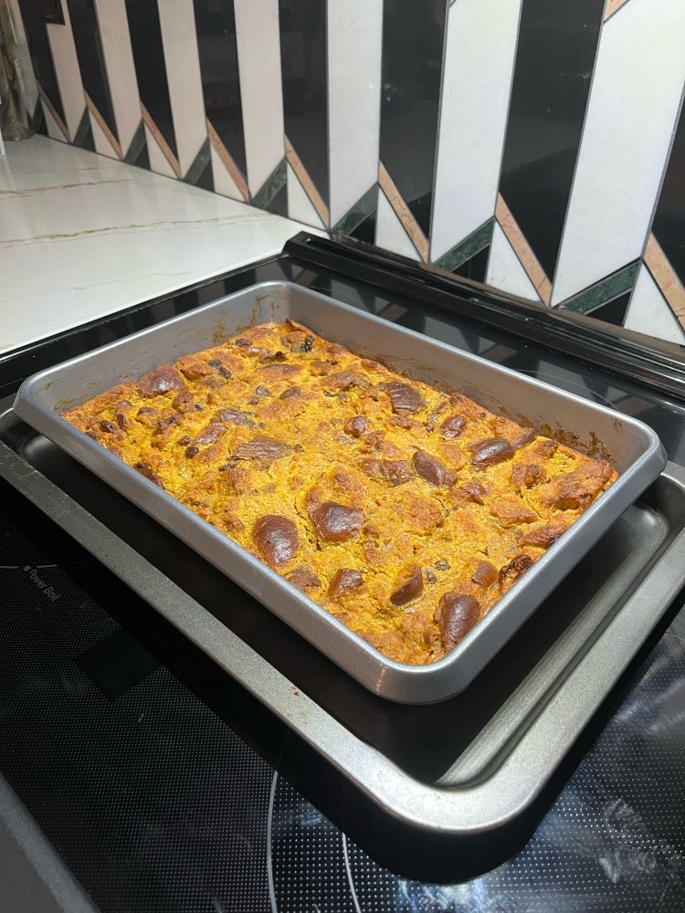 A tray of pumpkin bread pudding on a stove.