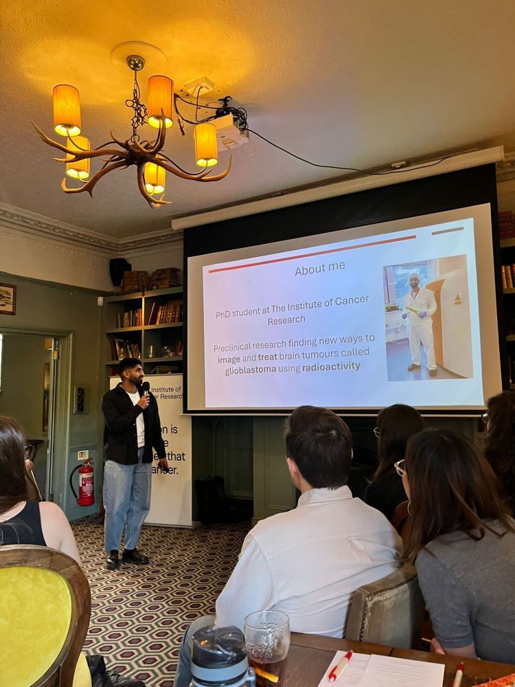 Presenting in the pub at Pint of Science. An About me slide is on the projector.