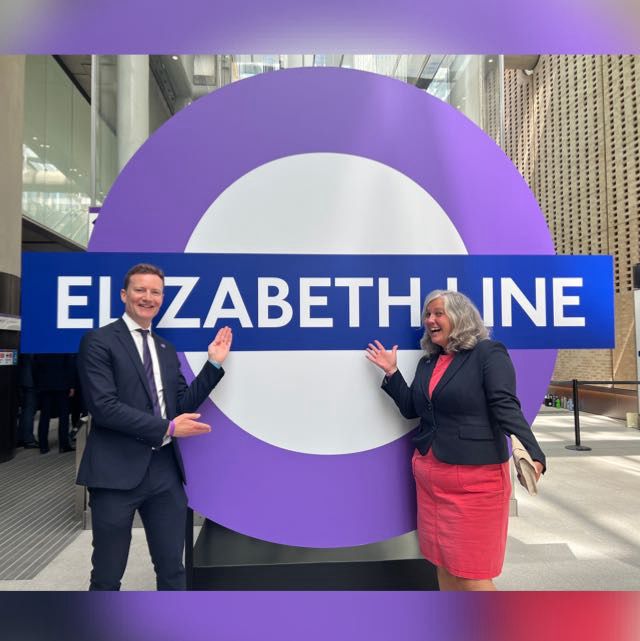 Seb stands with Heidi Alexander MP, now Secretary of State for Transport, in front of a giant Elizabeth line roundel