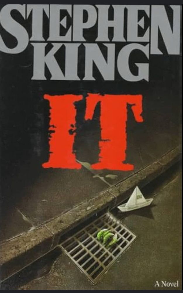 Book cover for the novel It by Stephen King. A photo of a paper boat floating towards claws rising out of a drainage grate by the street curb.