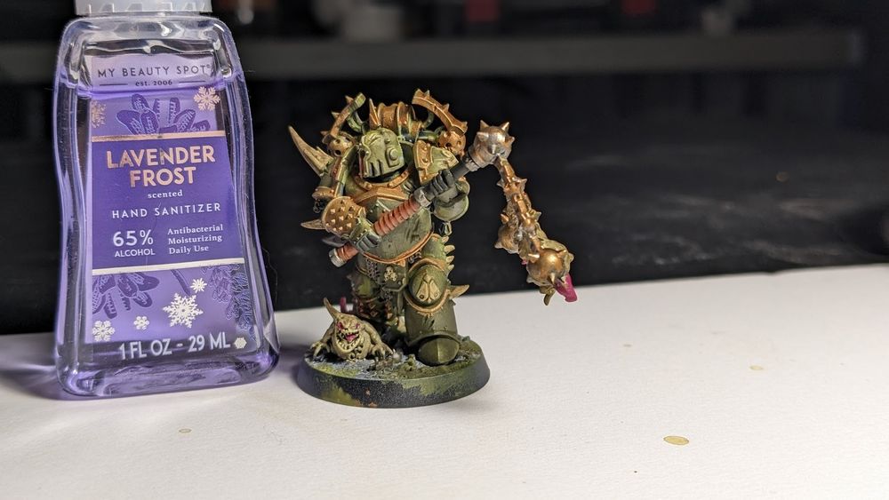 Side shot of a painted Warhammer 40k Death Guard miniature with flail posed next to a 29ml bottle of lavender-scented hand sanitizer for scale