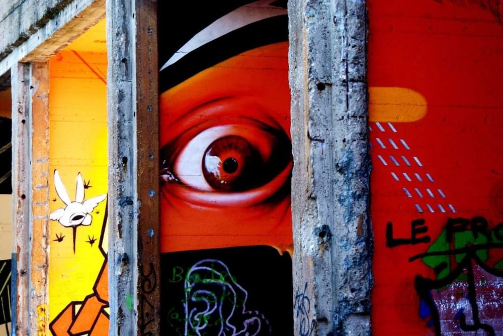 Eine Wand, die ein großes, aufgerissenen, rotes Auge auf rotem Hintergrund zeigt.