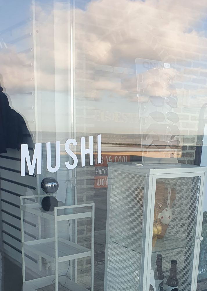 Eine Schaufensterscheibe auf der in weißen großen Buchstaben Mushi steht.